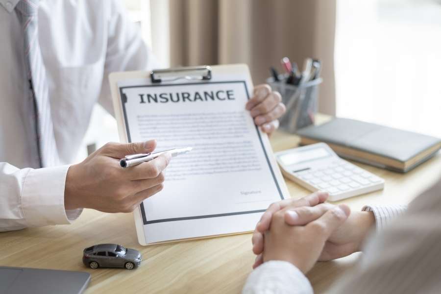 Un conseiller présente un document d'assurance pour aider un client à choisir la meilleure assurance-vie.